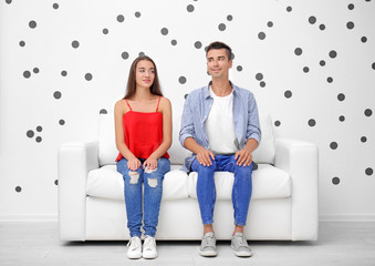 Obraz premium Young couple on sofa near white wall