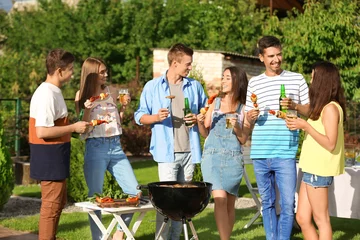 Fotobehang Young friends having barbecue party in garden © Africa Studio