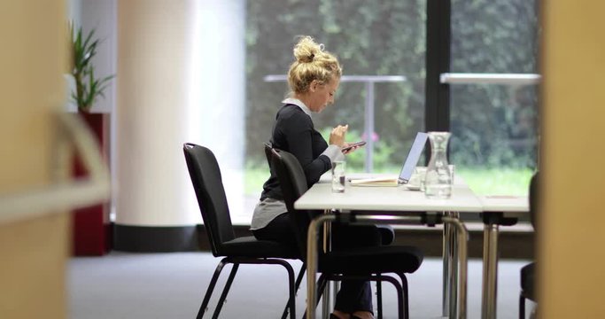Young business executive syncing smartphone with laptop
