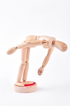 Human wooden dummy bending down. Yellow wooden dummy bending down over white background. Wooden mannequin in action.