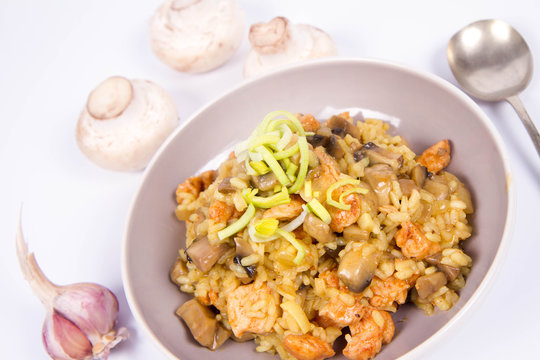 Risotto with mushrooms and chicken decorated with leek on a white background with some mushroom and garlic