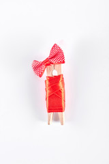 Clothespin in red apparel, white background. Wooden clothes peg in red dress and bow isolated on white background. Creativity and art.
