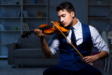 Young musician man practicing playing violin at home