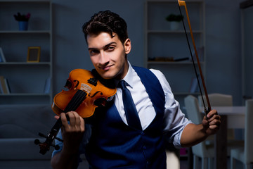 Young musician man practicing playing violin at home