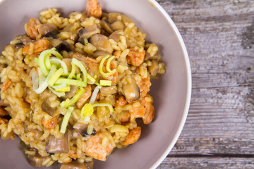 Risotto with mushrooms and chicken decorated with leek on a wooden background