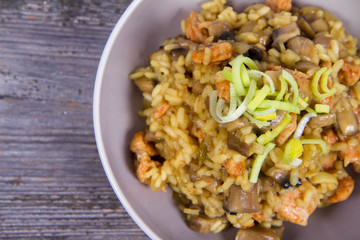 Risotto with mushrooms and chicken decorated with leek on a wooden background