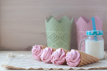 Pink raspberry flavour marshmallows or zephyr with milk on the wooden background