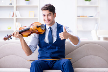 Young musician man practicing playing violin at home