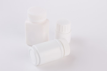 Different sizes white bottles for pills. Blank small, big and medium sizes plastic packaging bottles with cap for cosmetics or vitamins.
