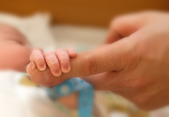 The baby clings to his father's finger