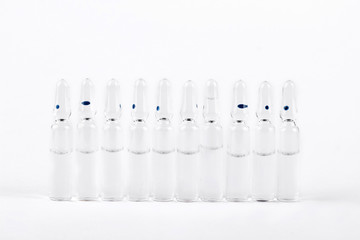 Raw of glass medical ampoules. Break-seal glass ampules with medicine liquid for injection on white background.