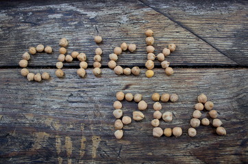 The word chickpeas from peas on a wooden basis