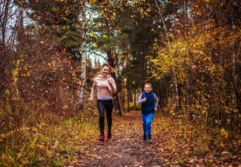 Naklejka na ściany i meble Little boy and his sister running in autumn forest