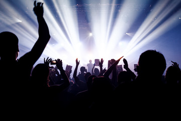 silhouettes of concert crowd in front of bright stage lights. pacifism sign on paper