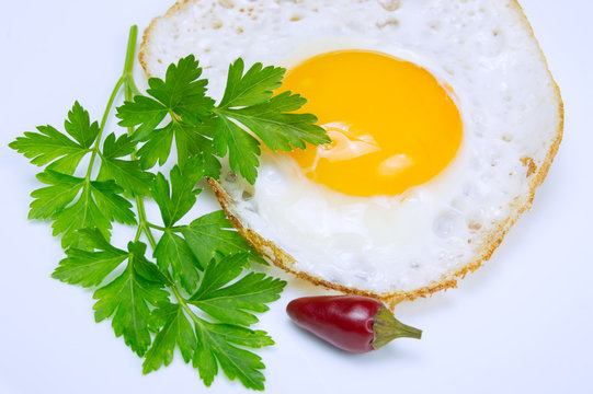 Fried egg with green parsley on plate with pepper close up on white background