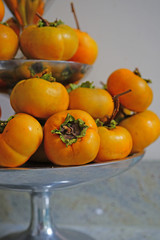 Orange persimmon kaki fruits freshly picked in the fall on a silver pedestal