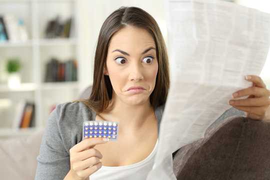 Confused girl reading leaflet of contraceptive pills