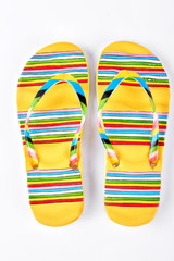 Summer fashion striped slippers. Yellow flip flops in colorful stripes isolated on white...