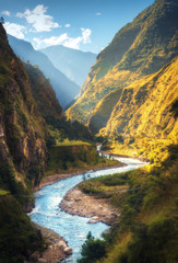Erstaunliche Landschaft mit hohen Himalaya-Bergen, schönem geschwungenem Fluss, grünem Wald, blauem Himmel mit Wolken und gelbem Sonnenlicht im Herbst in Nepal. Bergtal. Reisen Sie im Himalaya. Natur