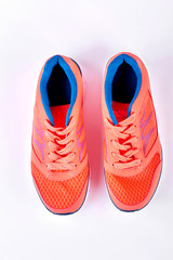 Orange sport shoes, top view. Female running sneakers isolated on white background. Fitness and healthy lifestyle concept.