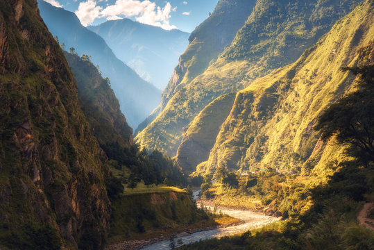 Fototapeta Amazing landscape with high Himalayan mountains, beautiful curving river, green forest, blue sky with clouds and yellow sunlight in autumn in Nepal. Mountain valley. Travel in Himalayas. Nature