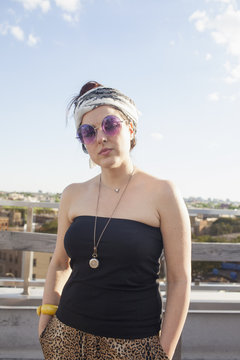 Portrait of a young woman wearing sunglasses and a bandana