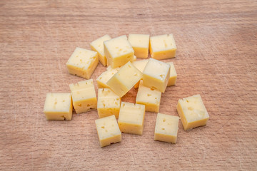 Cheese is cut into cubes on a board