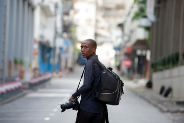 young man walks in the city with backpack and camera