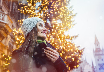 Frau schaut sich den Weihnachten Schmuck der Stadt an während es schneit