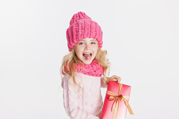 Christmas. New Year. Little girl holding present in winter clothes. Pink hat and scarf. Winter