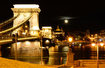 Night cityscape of Budapest with St. Stephen's Basilica, Danube river, Szechenyi Chain Bridge and full moon above the city