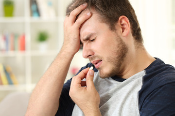 Man suffering headache taking a pill