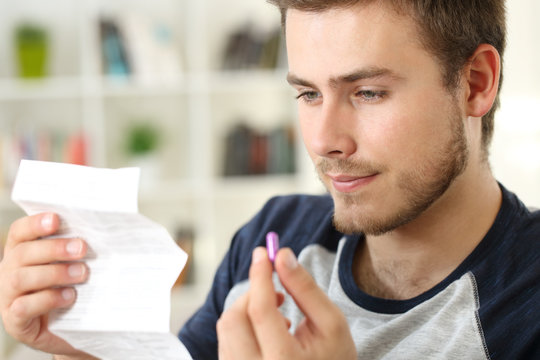 Man reading a leaflet before to take a pill