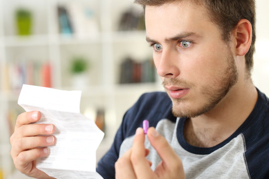 Shocked man reading a leaflet before to take a pill
