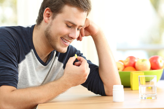 Happy Man Taking A Vitamin Pill At Home
