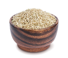 Brown rice groats in wooden bowl isolated on white background