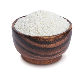 Small crushed rice groats in wooden bowl isolated on white background