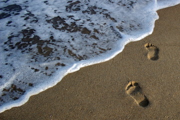 Footprints in the sand go to the sea