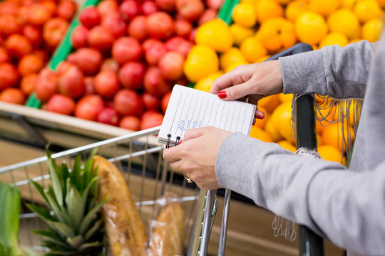 Woman with notebook in grocery store, closeup. Shopping list on paper.