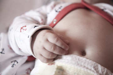 little baby hand, tummy and belly button in the bed - obrazy, fototapety, plakaty