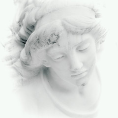Face of beautiful angel. Close up of marble sculpture with a sweet expression that looks down. (faith, religion, Christianity, death, immortality concept)