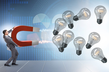 Businessman catching light bulbs on horseshoe magnet
