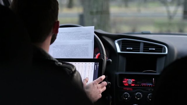 young man using a tablet in the car. student performing tasks in the car. Frilaser working in the car