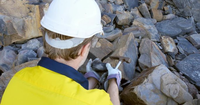 Geologist braking coal sample with pick axe mining exploration 