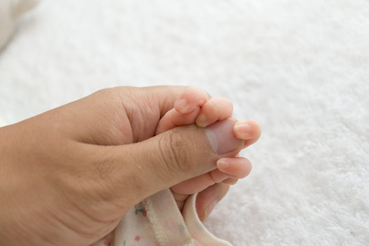 Newborn baby touching his father hand
