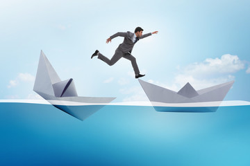 Businessman escaping sunken paper boat ship