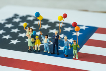 miniature happy american family holding balloons with president standing on United State national flag as festival celebration