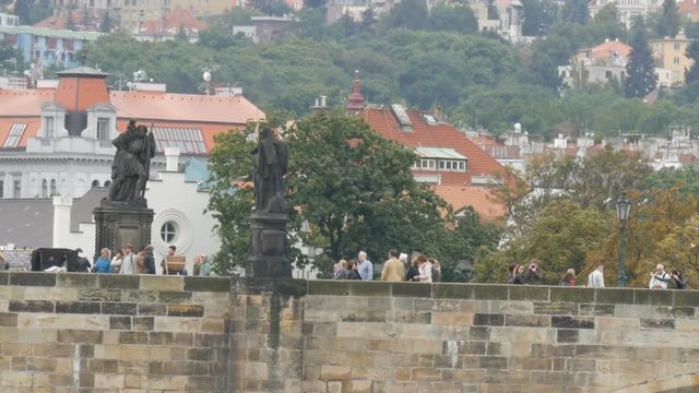 Prague Charles Bridge on Vltava River on which crowds of tourists stroll
