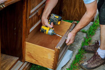 A workman fixing cabinet with screwdriver in kitchen