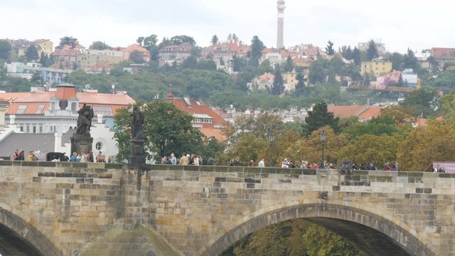 Prague Charles Bridge on Vltava River on which crowds of tourists stroll